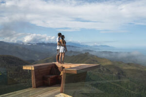 Matai Peak Experience Couple Stands On Overhang Admiring Amazing View